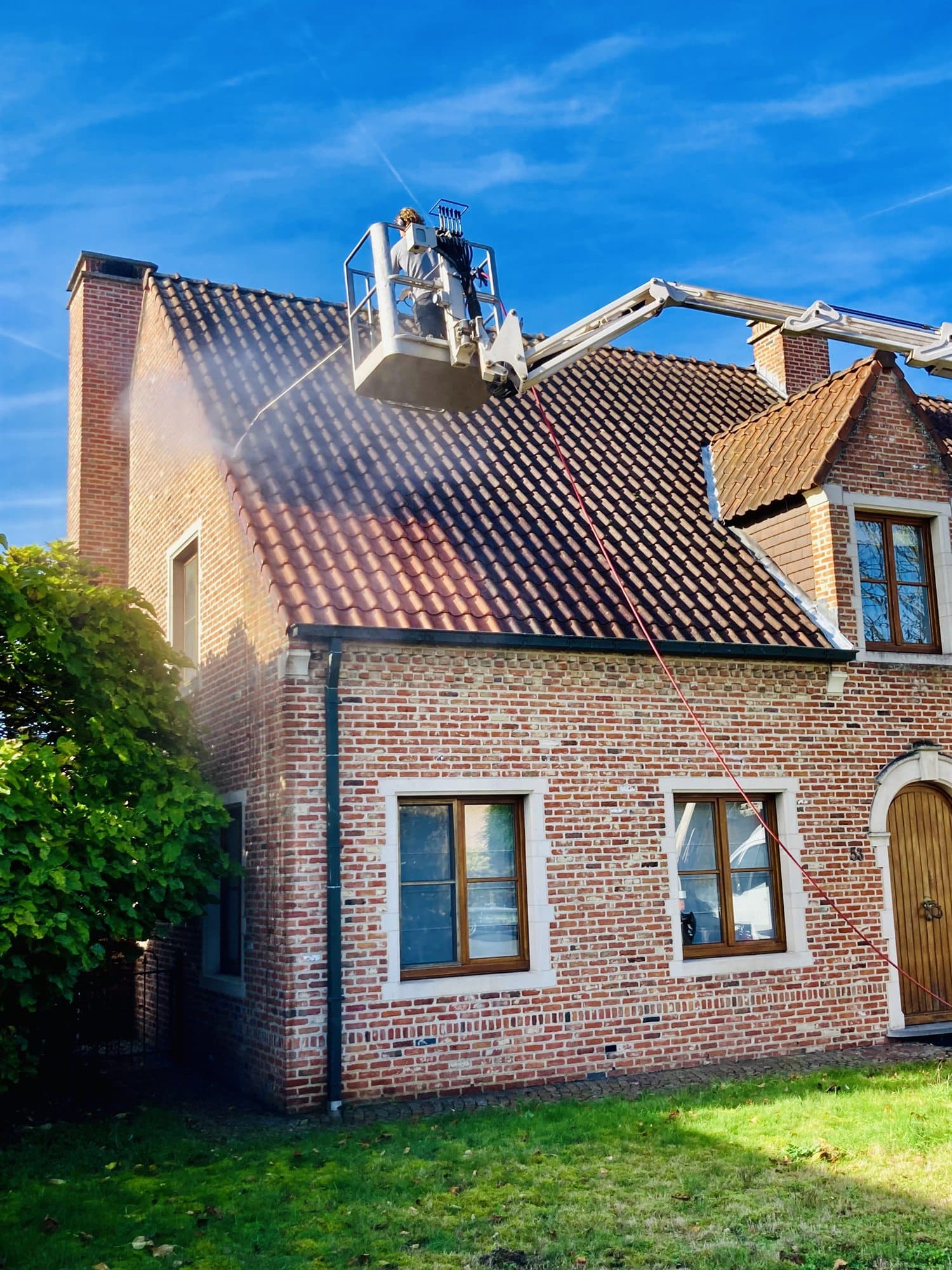 Hoogtewerker van Eco-Steam bij de gevel en het dak van een woning