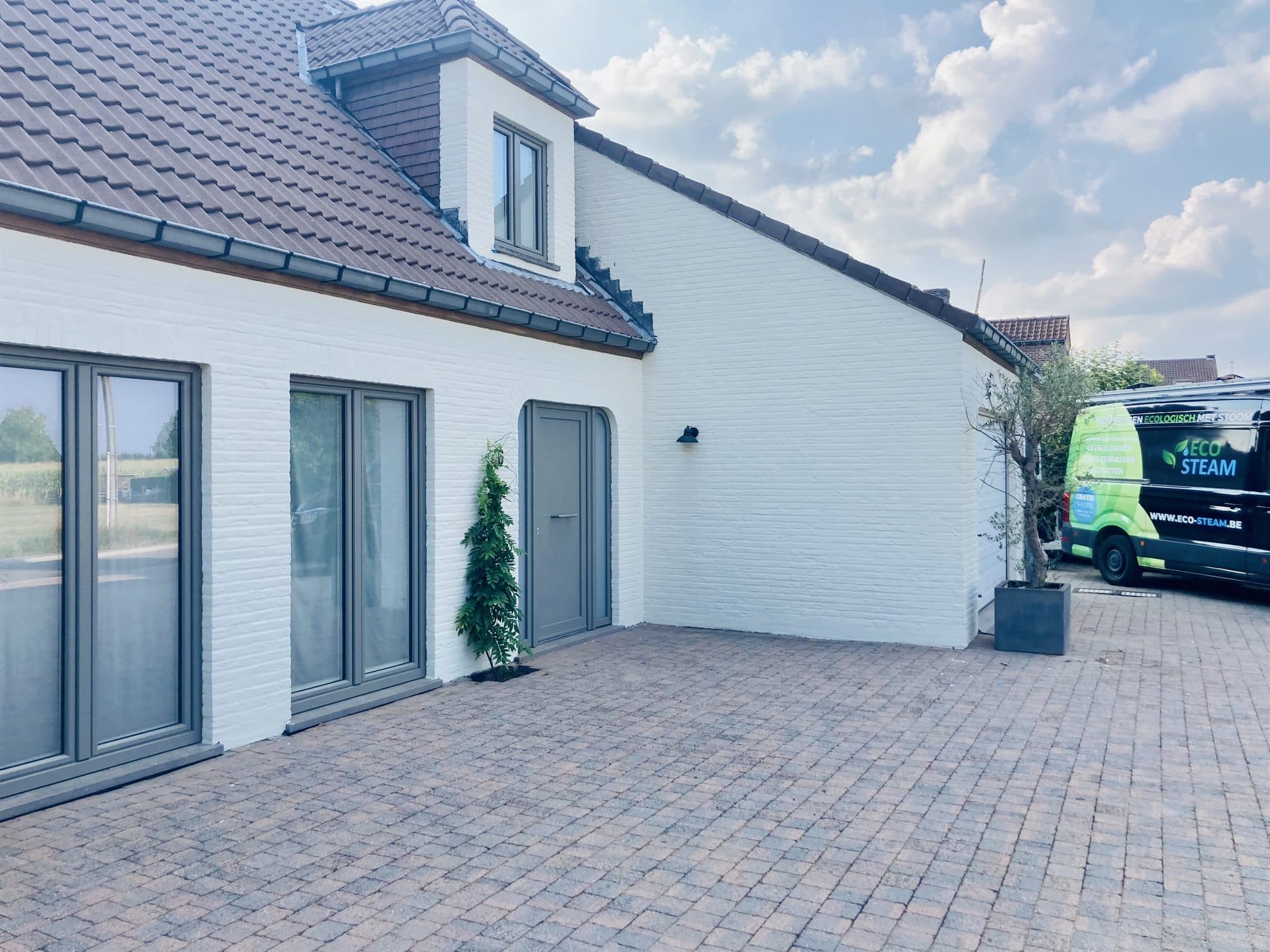 Gereinigde oprit bij een witte woning, met de bestelwagen van Eco-Steam