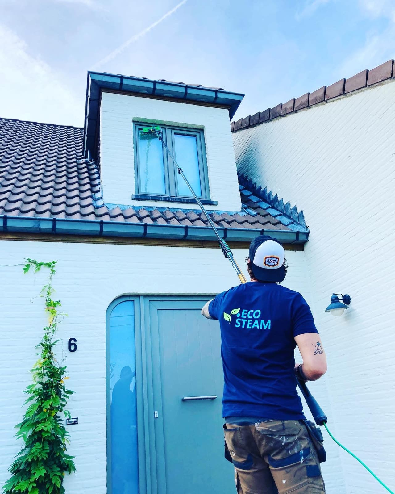 Medewerker van Eco-Steam reinigt een gevel met een telescopische lans