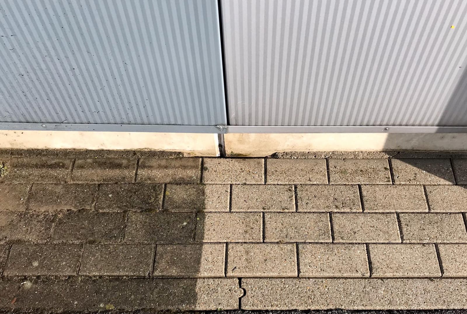 Verharding aan een bedrijfsgebouw, half gereinigd