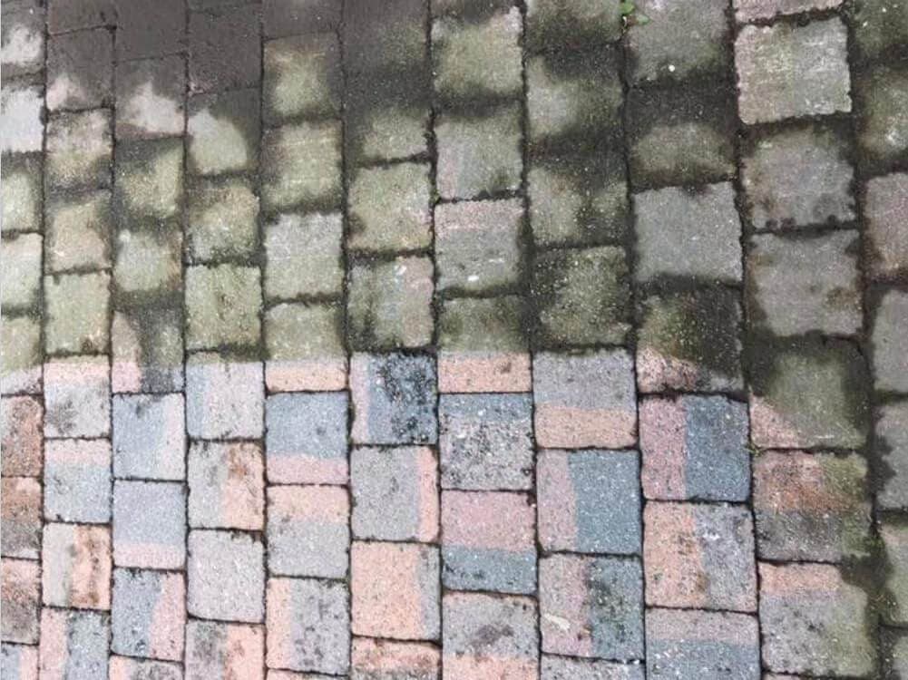Klinkerverharding waarvan de onderste helft gereinigd is en de bovenste helft groen uitgeslagen